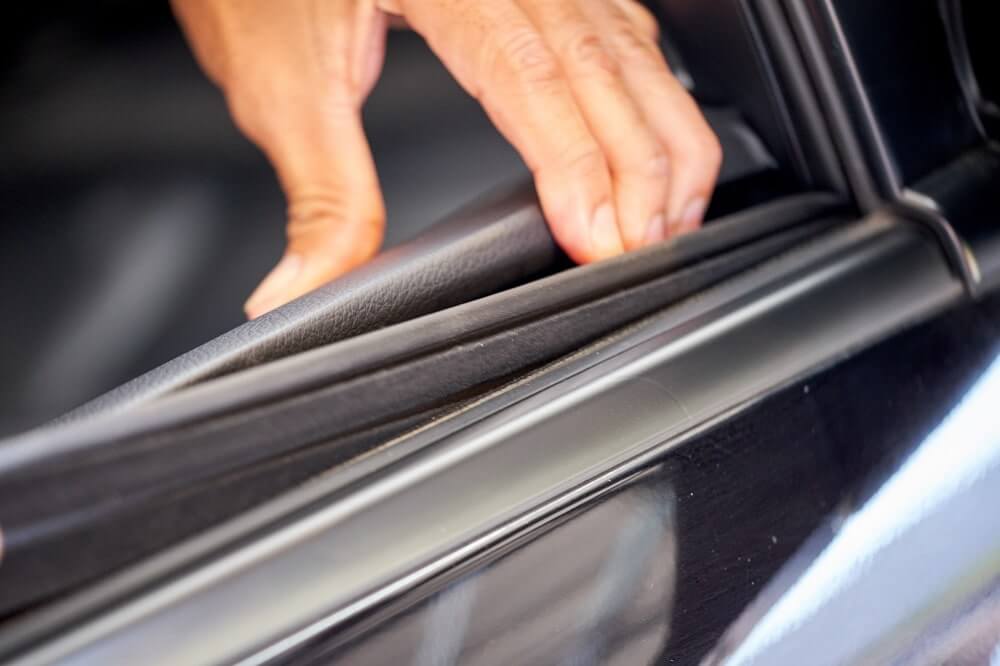 A person’s hand on a rubber window seal for a vehicle